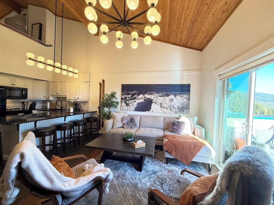 Relax on the oversized sectional framed by an aerial photograph of the Rocky Mountains — the ridge line visible from just outside that deck door.