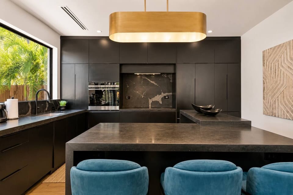 Pull up one of the blue stools at the island for a quick bite, with the oven and prep space close by if anyone wants to get cooking while the gold pendant light sets the mood.