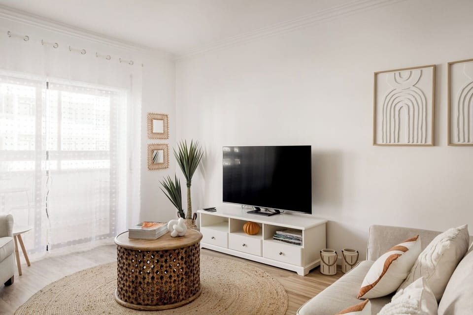 Living room with TV and dining table. Opens onto an enclosed balcony - a bright little retreat.