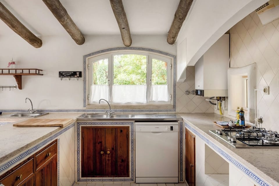 With wooden beams and tiled countertops, this fully equipped kitchen blends rustic charm with practicality.