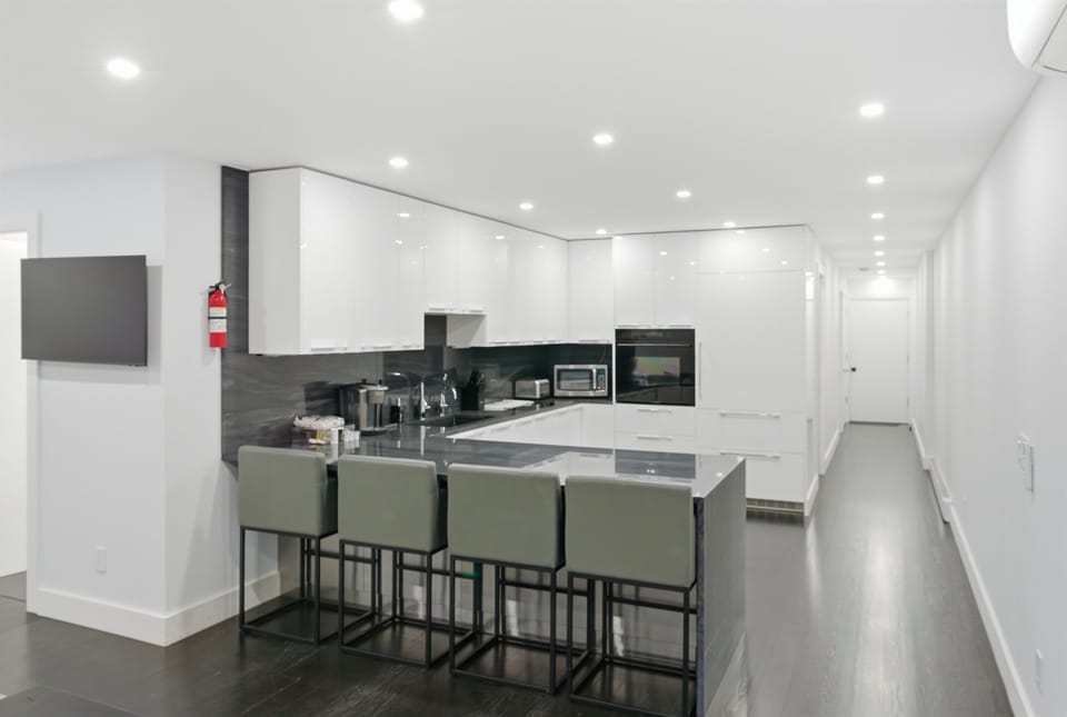 Chef’s kitchen in the heart of downtown Bar Harbor, featuring professional Wolf and Miele appliances, waterfall countertops, and bar seating for four. This sophisticated space includes full climate control with air conditioning.