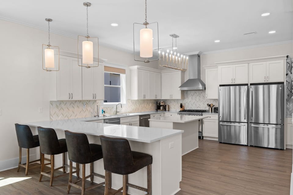 Step into your bright, modern kitchen where sleek white cabinetry meets gleaming quartz countertops and designer lighting creates the perfect ambiance for memorable meals together.