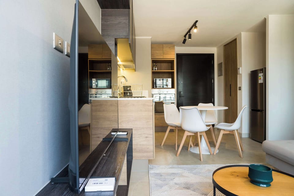Open-plan living and dining area with a wood-finished kitchen island, built-in appliances, and seating for four.