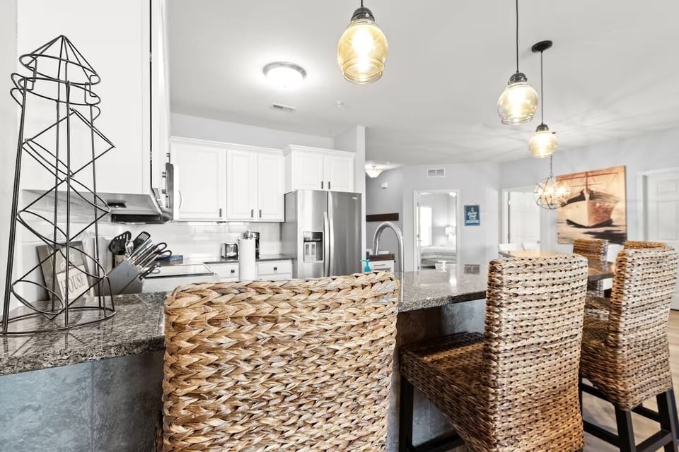 Your modern kitchen features granite countertops, stylish pendant lighting, and woven bar stools where you can enjoy meals together.