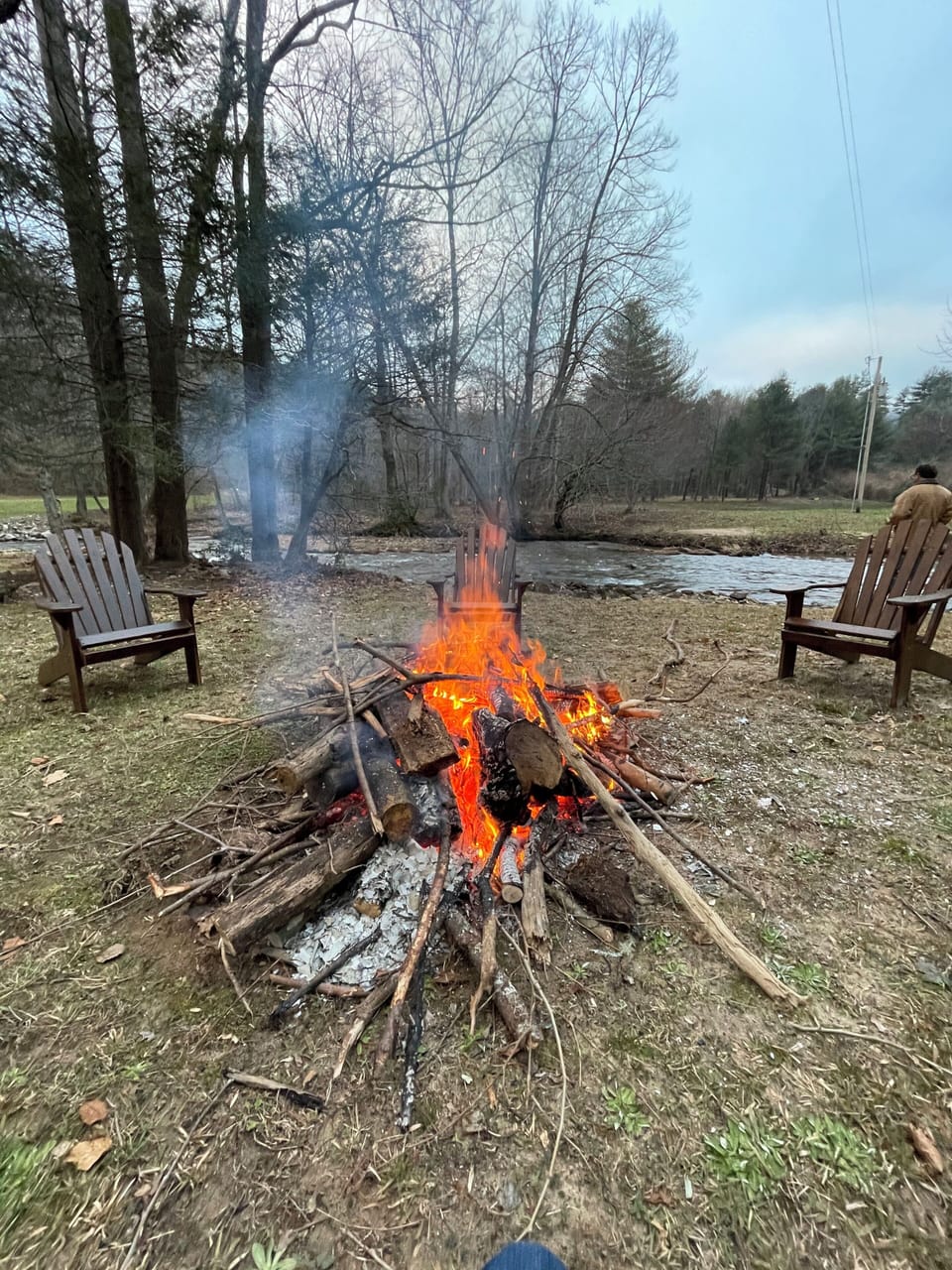 Fire pit with Adirondack chairs next to Cooper's Creek