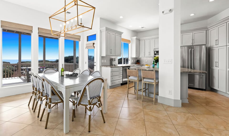 Your gourmet kitchen flows seamlessly into the dining area, where morning coffee meets stunning Gulf views through floor-to-ceiling windows.