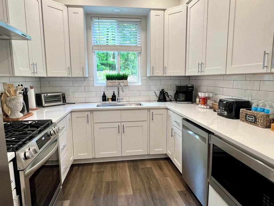 Bright modern chef's kitchen with quartz, gas range, coffee station, garden view.