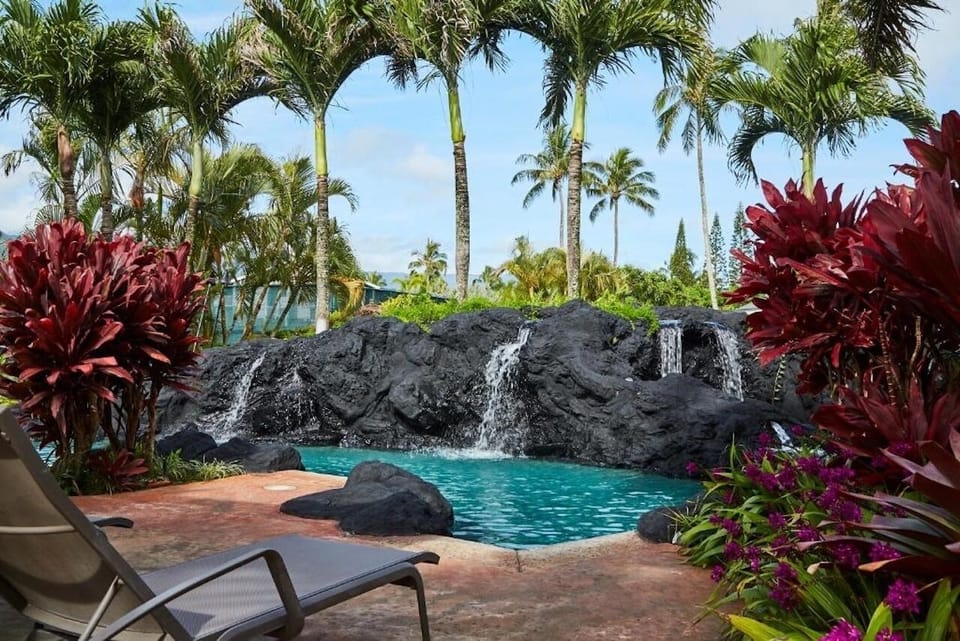 Unwind beside the lava-rock waterfall pool under palms.