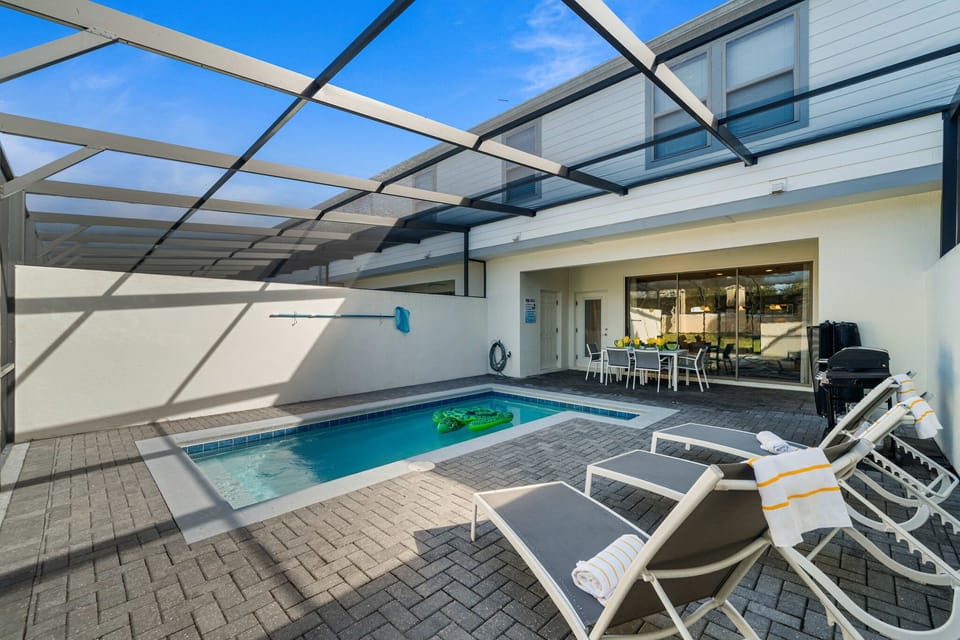 Poolside paradise steps from the living room: splash in the screened pool, stretch out on the loungers with towels, and dine alfresco under the covered patio.