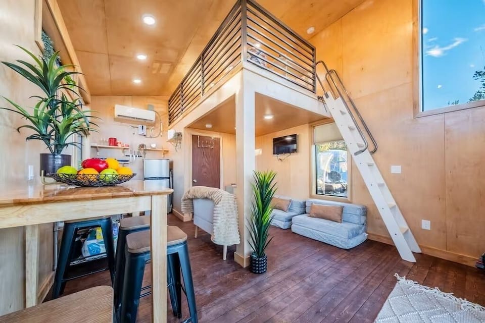 A shot of the living room, loft, bathroom (door) and kitchen area.
