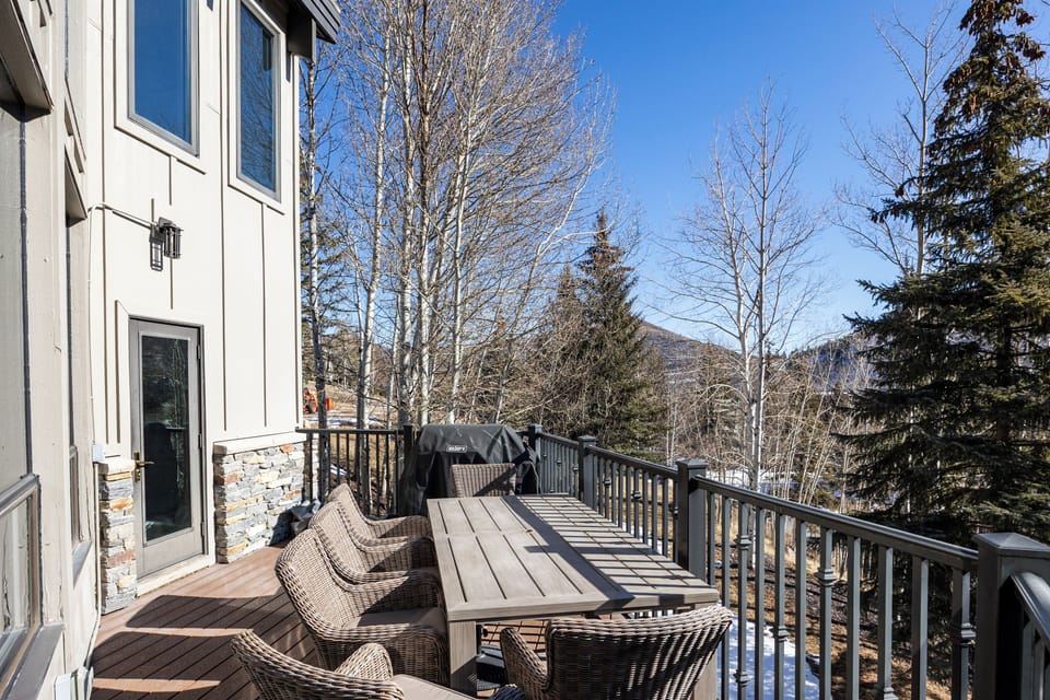 Spacious private deck featuring a BBQ grill and outdoor dining seating, surrounded by trees for a peaceful mountain setting—great for meals and relaxing outdoors.