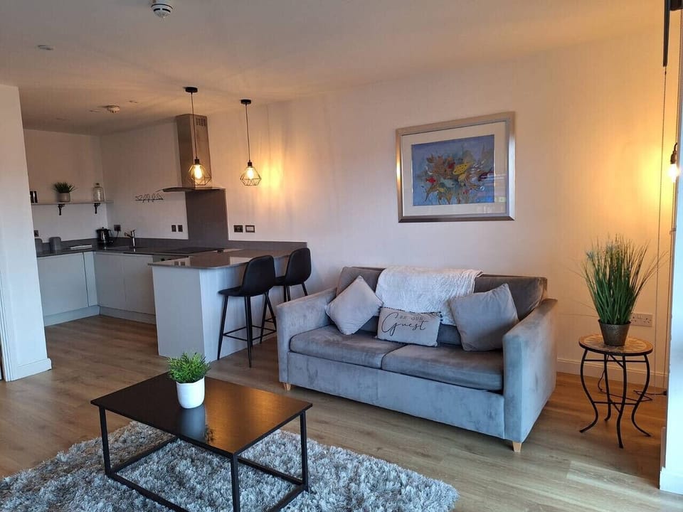 The open-plan living area includes a sofa, breakfast bar stools, and pendant lighting.