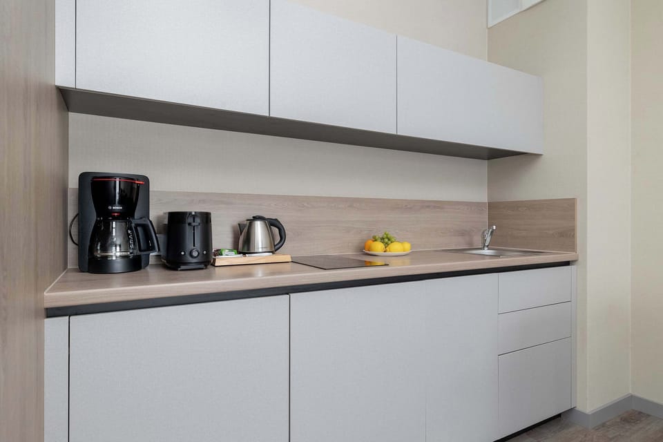 A modern kitchen countertop with cabinets and small appliances. The design is clean and practical.