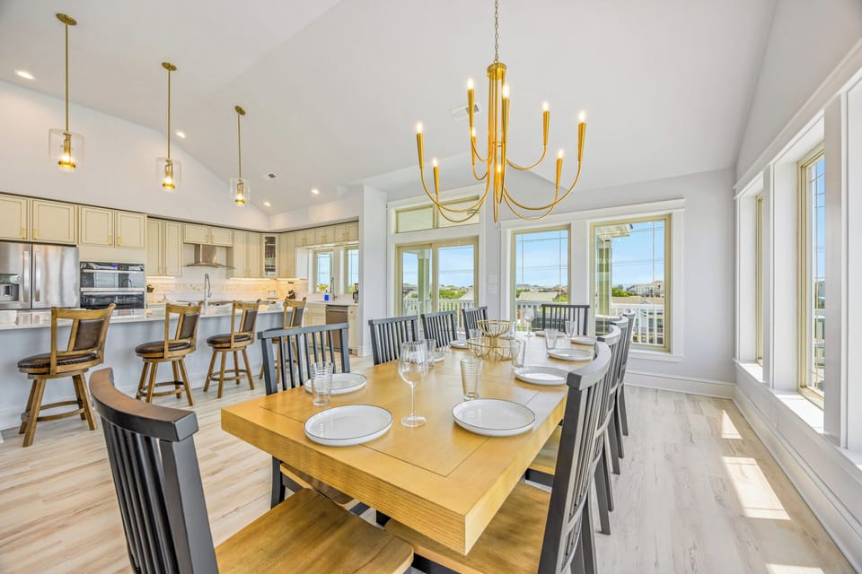 Gather around the elegant dining table where sunlight streams through expansive windows, or relax at the kitchen island—this inviting space is perfect for shared meals and vacation memories.