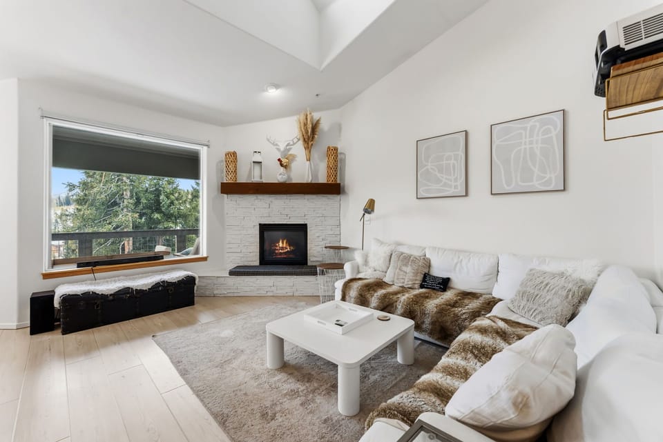 Sink into plush seating by your fireplace while enjoying tree views through large windows in this bright, modern living space.