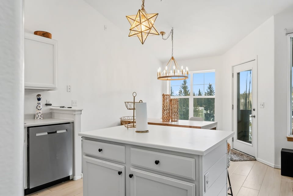 Your bright kitchen welcomes you with stunning star pendant lighting and forest views through the window.