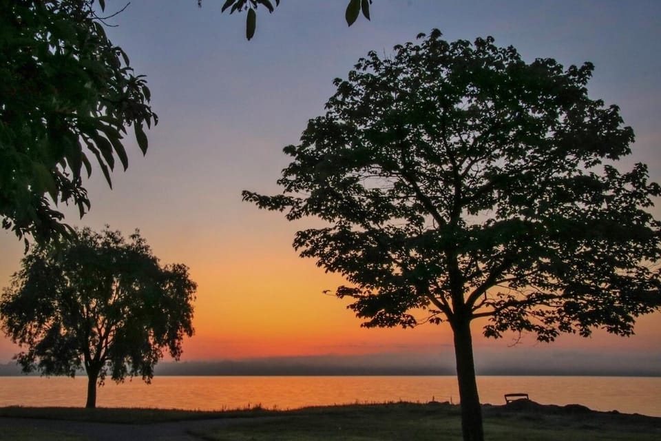 Unwind at sunset with peaceful lakeside colors and calm skies.