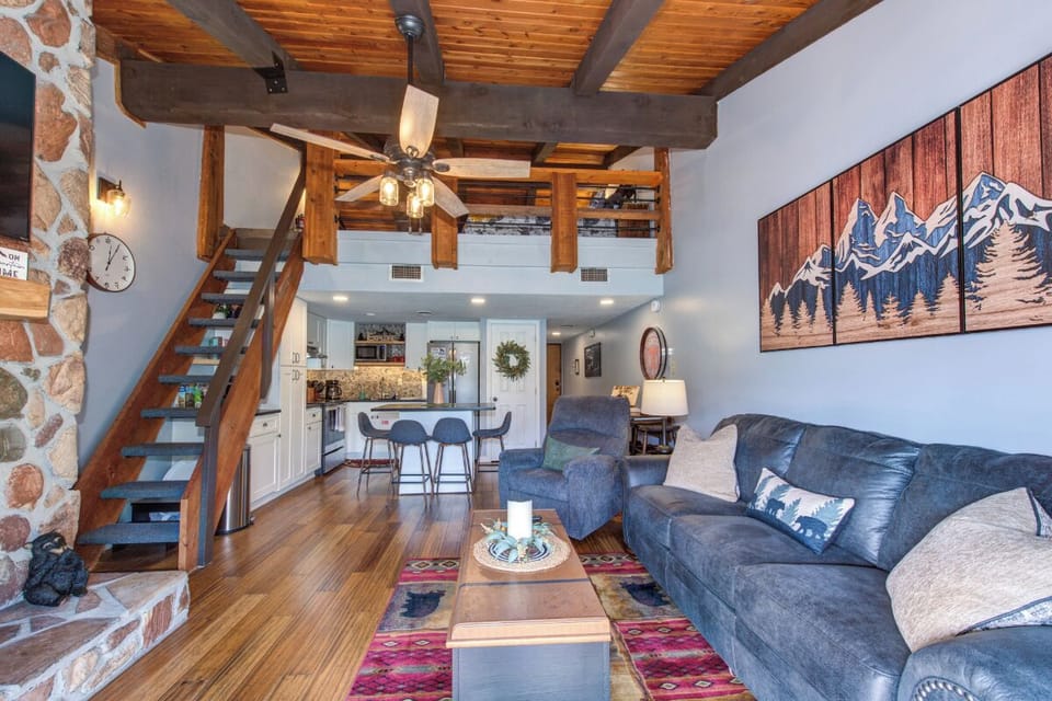 Unwind in your cozy mountain retreat with exposed beams, stone fireplace, and inviting living space perfect for relaxation.