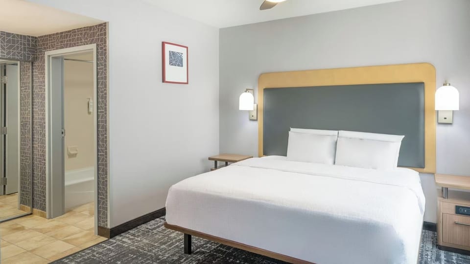 Sink into a plush bed framed by warm bedside lighting.