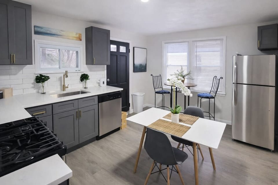 This modern, fully equipped kitchen features sleek gray cabinetry and stainless steel appliances, complete with a cozy breakfast bistro set perfect for enjoying your morning coffee or tea.