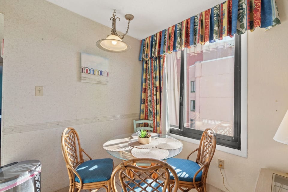 Your bright dining nook features colorful tropical curtains and wicker seating, perfect for morning coffee while watching the world wake up outside.