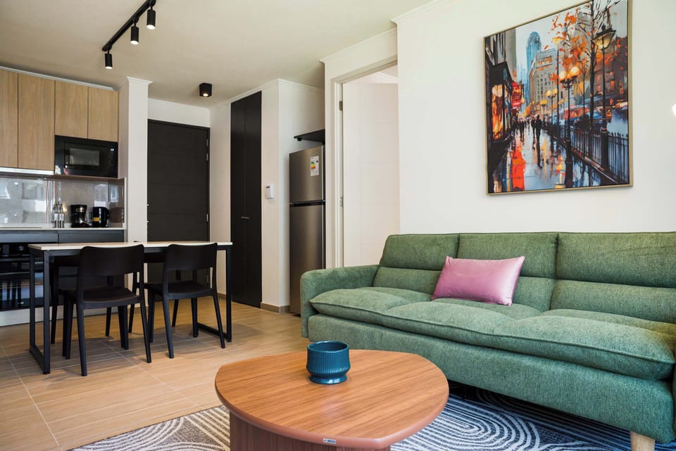 Modern living area with a cozy green sofa and stylish kitchen, perfect for relaxing after exploring the city.