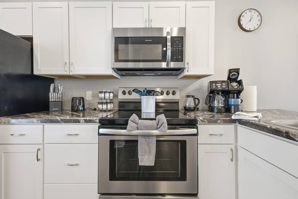 Modern kitchen with stainless appliances, stocked coffee bar and tools.