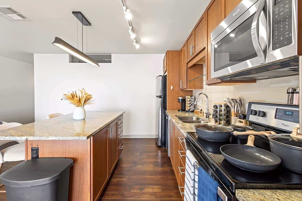 Modern kitchen with granite countertops, warm wood cabinetry, and a spacious island for prep or casual dining. Fully equipped with cookware and essentials, making it ideal for home cooked meals during your stay.