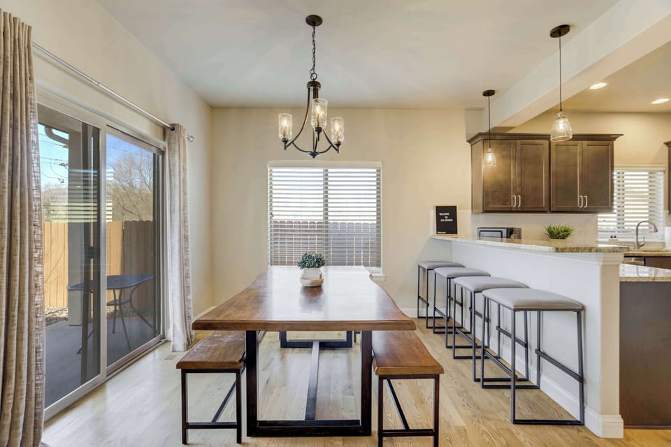 The dining area offers plenty of space for group meals and features a large wooden table with bench seating. This bright space connects directly to the private backyard and patio through large sliding glass doors.