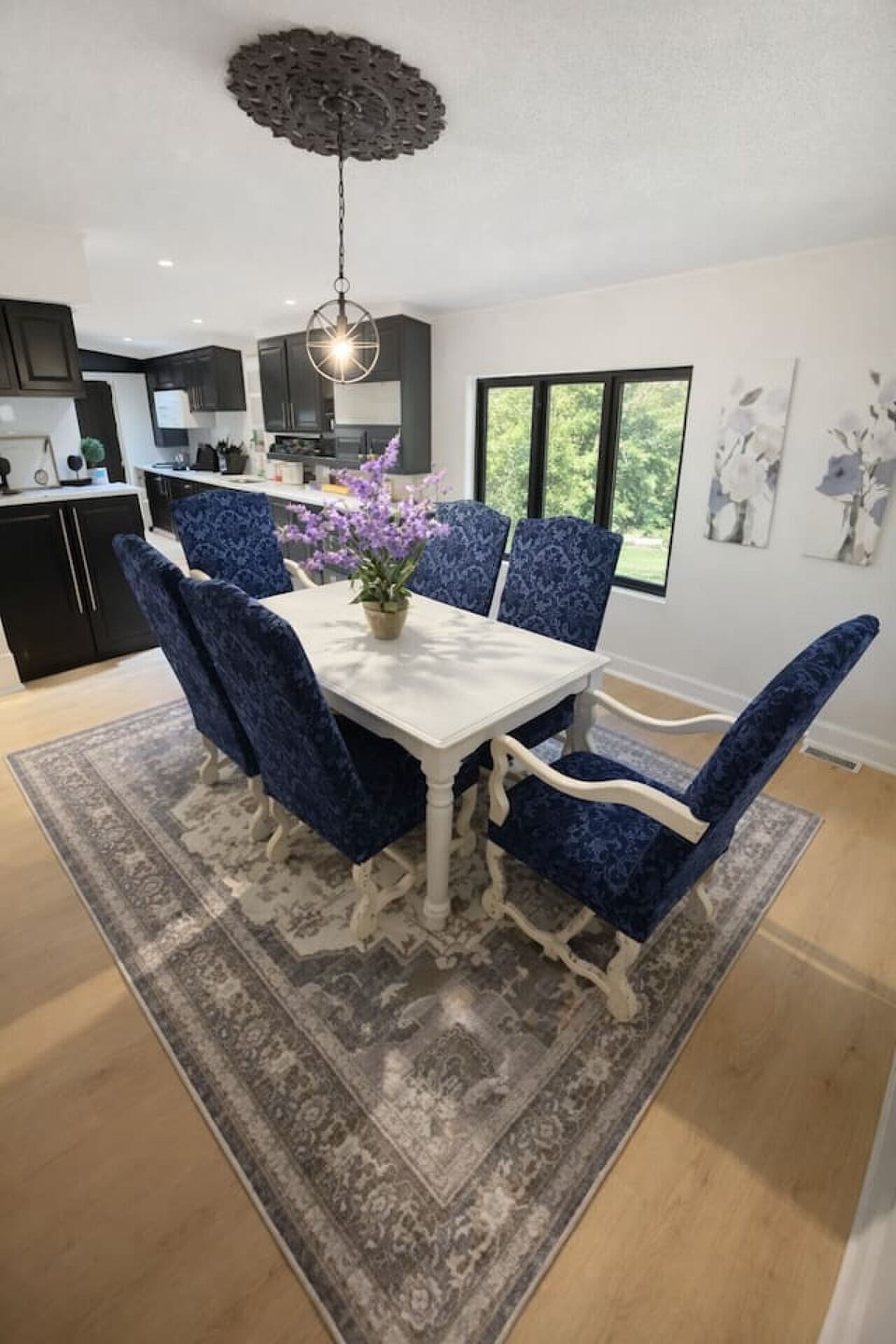 Gather around this elegant dining table, perfectly positioned under a modern chandelier to create a warm, inviting space for shared meals and conversation.
