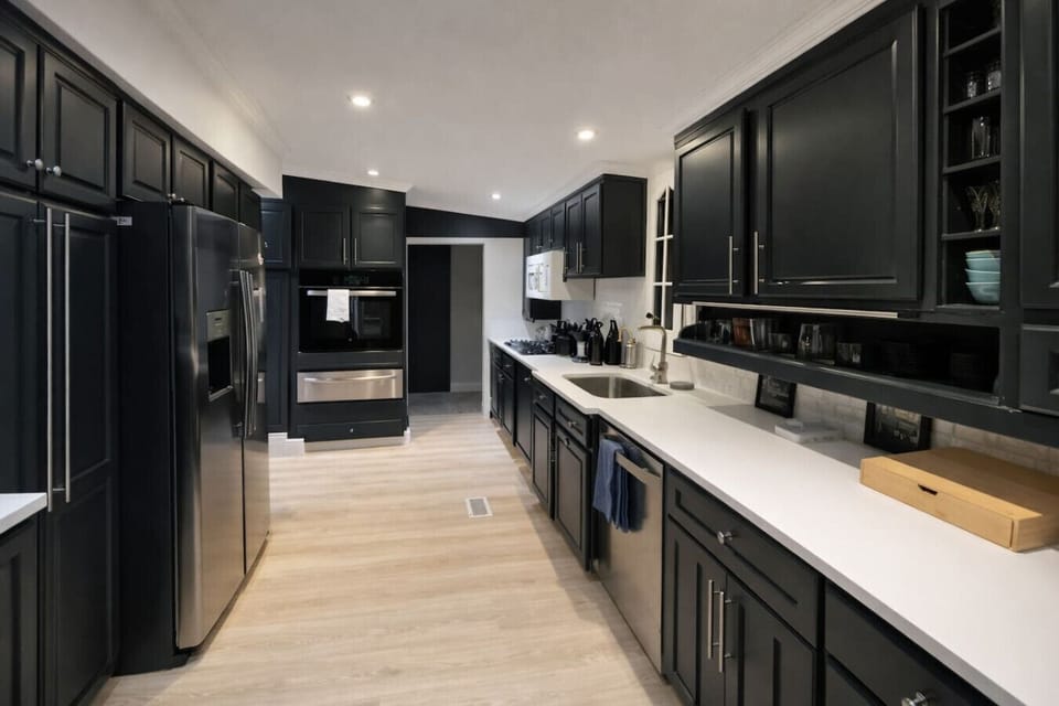 Cook with ease in this bright, contemporary kitchen featuring clean black cabinetry, high-end stainless steel appliances, and a convenient breakfast bar for casual morning coffee.