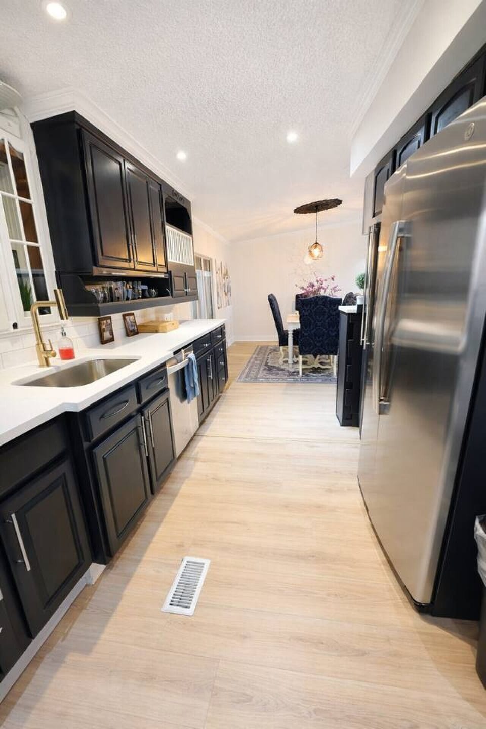 Cook with ease in this bright, contemporary kitchen featuring clean black cabinetry, high-end stainless steel appliances, and a convenient breakfast bar for casual morning coffee.