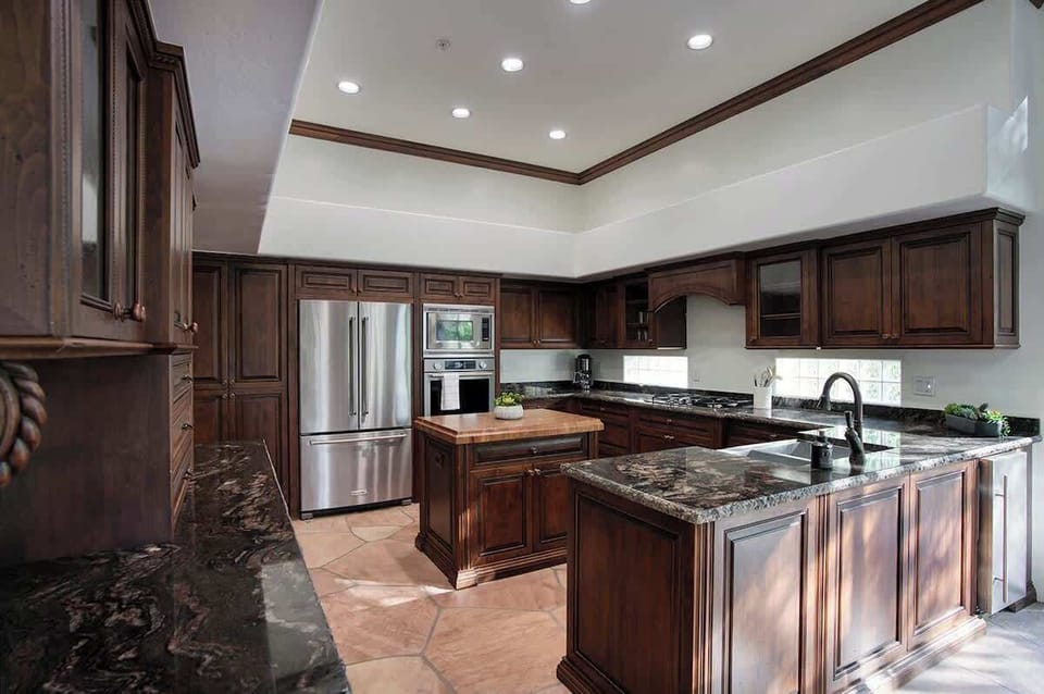 Fully equipped kitchen with stainless steel KitchenAid appliances, dual kitchen sink, a sleek kitchen island, endless counterspace, and cabinets.