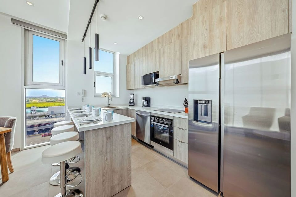 Cook with style in your modern kitchen, featuring stainless steel appliances and stunning views through floor-to-ceiling windows.