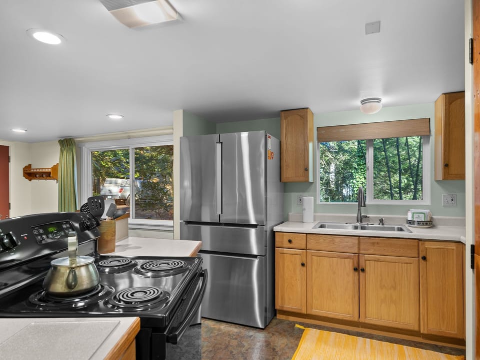 Cook your favorite meals in this spacious kitchen featuring stainless steel appliances, warm wood cabinets, and garden views through large windows.