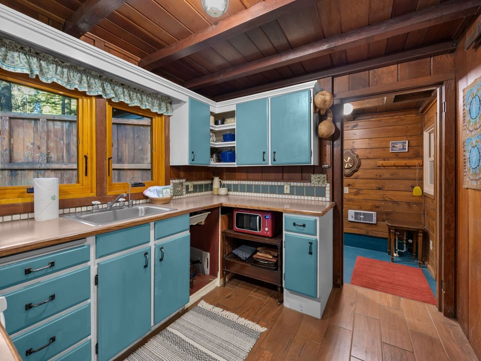 Step into your charming rustic kitchen with exposed beam ceilings, turquoise cabinets, and all the essentials for preparing memorable meals together.