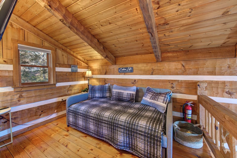 Your cozy loft bedroom features warm wood beams and plaid bedding for restful mountain nights.