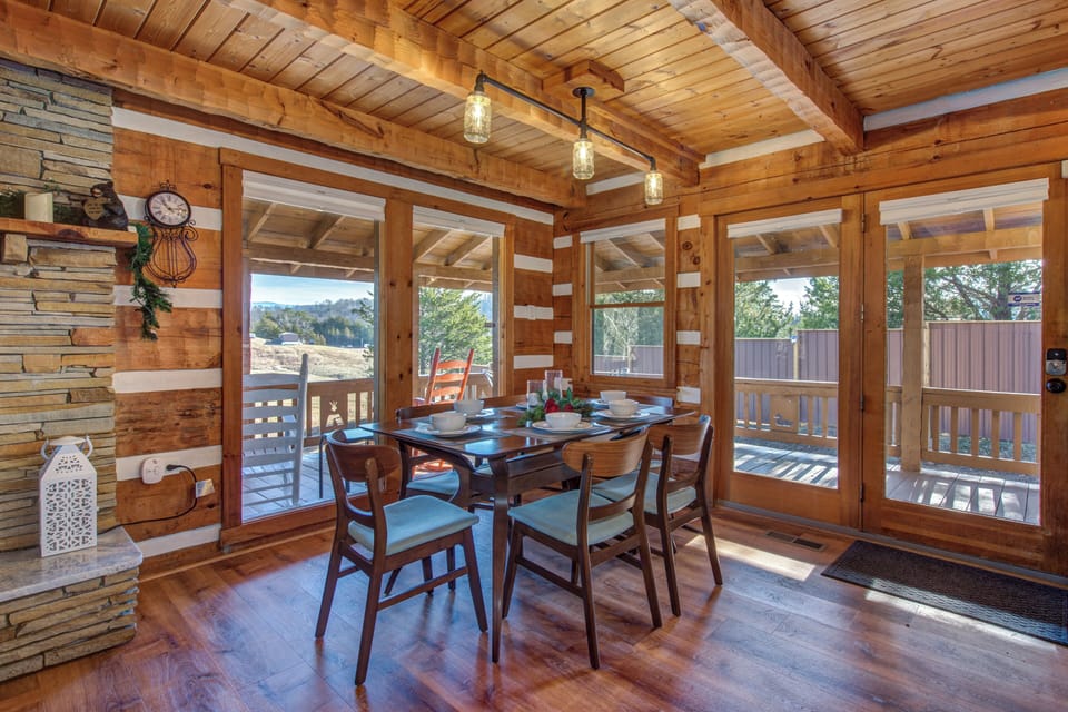 Gather around your rustic dining table where warm wood beams and panoramic windows create the perfect setting for memorable meals together.