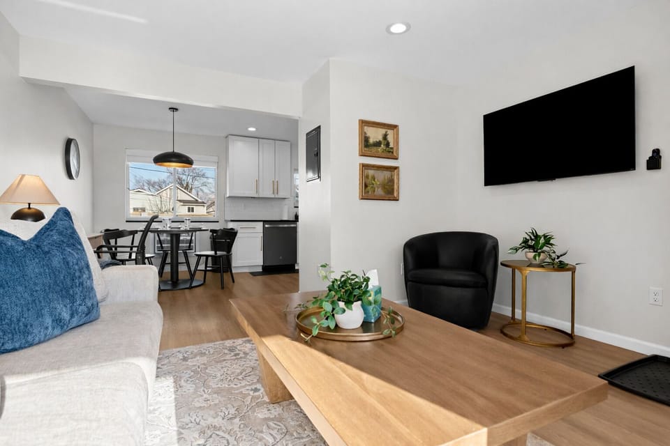 Unwind in this airy, open-concept living area featuring stylish seating, a smart TV, and seamless flow into the dining space and modern kitchen.