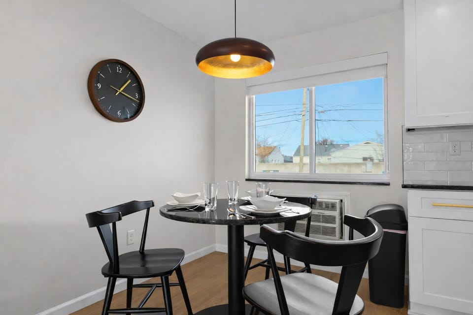 Bright, modern dining area with chic seating, warm pendant lighting, and a sunny window—ideal for casual meals or a relaxed dinner at home.