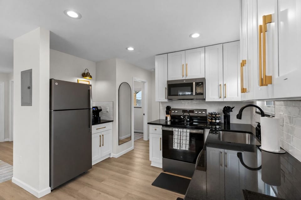 Bright, modern kitchen with sleek black appliances, quartz countertops, and ample storage—fully equipped for easy meals, morning coffee, and home-cooked favorites.