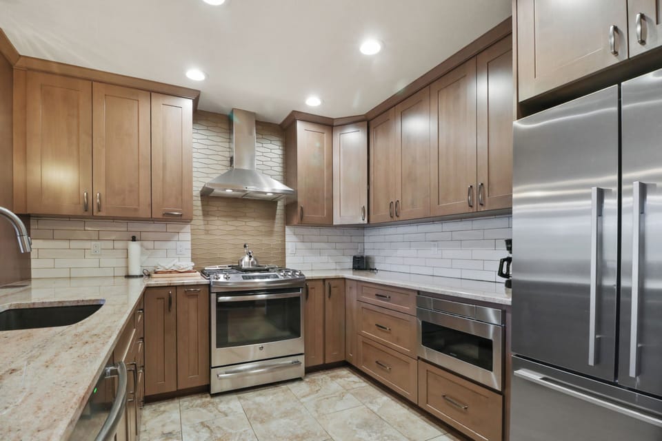 Your gourmet kitchen features sleek stainless steel appliances, warm wood cabinetry, and marble countertops for perfect meal preparation.