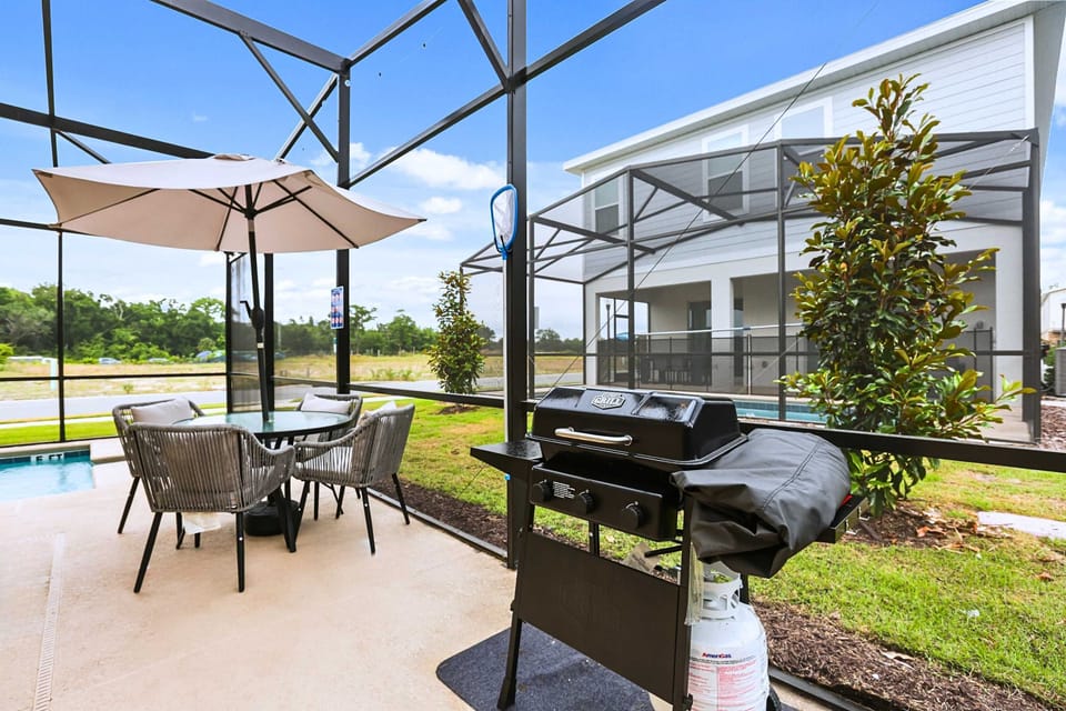 Shaded outdoor dining area with BBQ grill, perfect for poolside meals and relaxing evenings