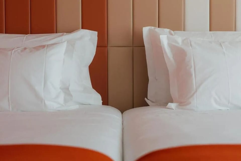 Recharge in twin beds wrapped in hotel-soft white bedding.