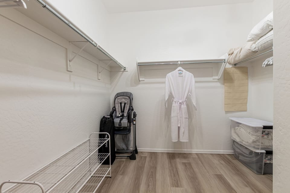 Large primary closet with robe, playpen, and bedding, highchair, queen mattress+