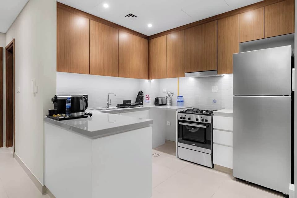 Bright and functional kitchen in Dubai featuring elegant wood finishes, spacious countertop and all the essentials, including a coffee machine and kettle.