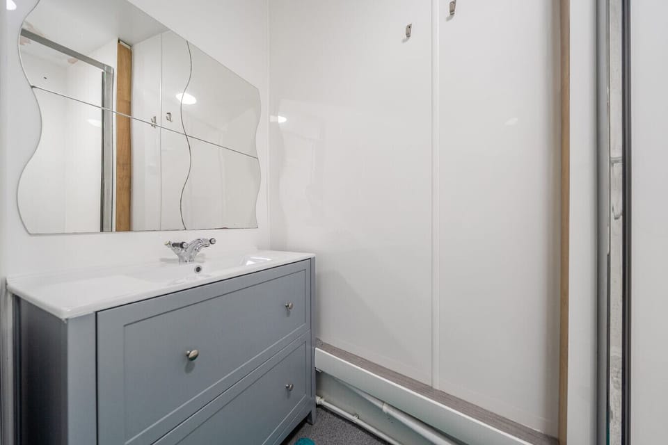 Grey vanity unit with sink beside a bathtub/shower surround