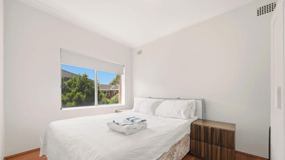 Comfortable double bedroom with large window views and neatly prepared linens.