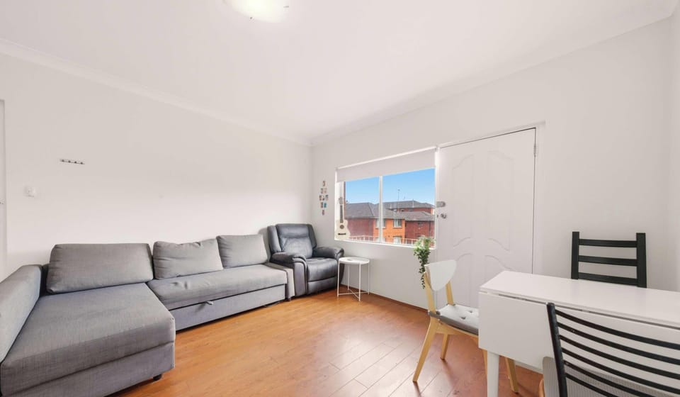 Spacious living area with a comfortable grey sofa (sofa bed) and natural light from large windows.