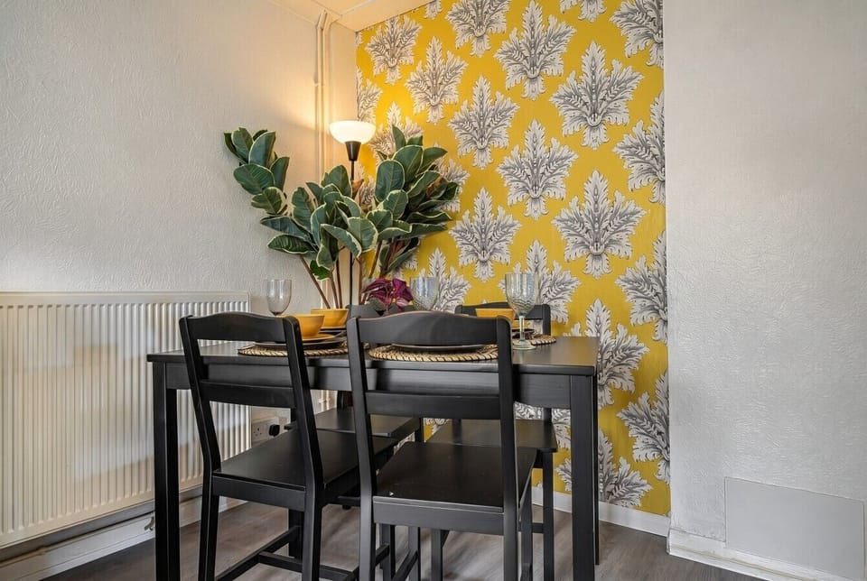 The bold botanical feature wall sets a cheerful mood around the dining table for four.